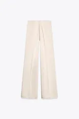 Pantalón de vestir color crema, de tela satinada, tiro alto y corte palazzo.