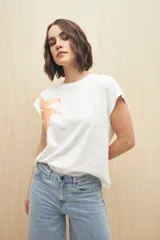Remera blanca de manga corta con estampado de una flor color durazno en el frente.