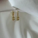 Aros colgantes dorados con forma de hojas y pequeños brillantes incrustados.