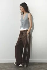 Pantalón de tiro alto negro a rayas verticales blancas, con cintura elástica ajustable con cordones, bolsillos delanteros y banda lateral blanca.