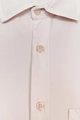 Camisa color crudo de corte recto, con cuello clásico, manga larga con puños abotonados, cierre frontal con botones y bolsillo de parche en el pecho.
