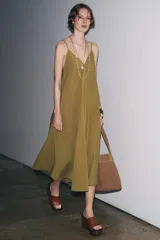 Vestido midi color ocre de Zara Woman Collection, confeccionado en hilatura con mezcla de algodón. Presenta escote pico, tirantes finos y tejido con volumen.