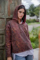 Buzo hoodie con estampado de piel de serpiente en tonos marrones y negros, con capucha forrada en color borgoña y cordón ajustable.