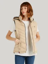 Chaleco acolchado Tommy Hilfiger color beige con capucha ajustable con cordones y cierre de cremallera frontal. Cuenta con bolsillos laterales con cremallera y detalles distintivos de la marca.