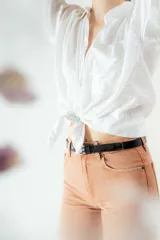 Cinturón negro de cuero charol con hebilla metálica plateada y ojales metálicos.