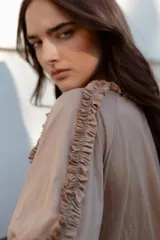 Blusa color beige de manga 3/4 confeccionada en algodón suave, con escote a la base y detalles de volados en 3D que recorren el frente, mangas y escote.