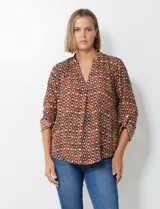 Blusa de gasa con estampado geométrico en tonos tierra (marrón, rojo, verde, amarillo). Presenta cuello solapa con escote en V y mangas largas ajustables con presilla y botón.