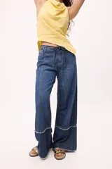 Pantalón de jean azul de corte recto y tiro bajo, con cintura ajustable con cordón y detalle de ruedo desflecado.