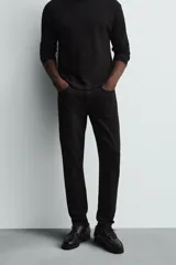 Pantalón de jean negro, corte slim fit, con tiro medio, cinco bolsillos, efecto lavado y cierre frontal con cremallera y botón.