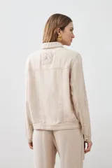 Chaqueta color beige melange de lino con pespuntes a contraste, cuello camisero, cierre frontal con botones, bolsillos de parche en el pecho y corte recto.