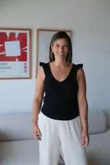 Musculosa negra de tejido fino, con escote en V y volados en los hombros.