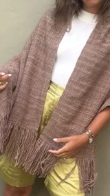 Ruana de lana merino tejida artesanalmente en telar, de color visón con diseño recto y terminación de flecos en los extremos.