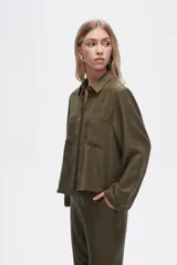Camisa color natural de poliéster con cuello camisero, cierre con botones, dos bolsillos frontales y corte ancho.