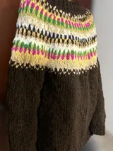 Sweater de lana merino con cuello redondo y diseño con motivos geométricos en tonos azul, marrón, naranja, verde y beige.