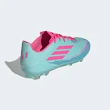 Championes de fútbol Adidas F50 League Messi, color celeste iridiscente con detalles en rosa fucsia. Presentan las tres franjas de Adidas en rosa en el lateral y la inscripción "MESSI F50" en la puntera. Tienen tapones transparentes y cordones rosas.