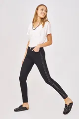 Pantalón jean slim negro con tachas plateadas en los laterales.