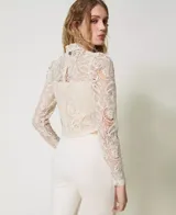 Blusa corta de encaje macramé color blanco, con cuello mandarín y mangas largas estilo guante.