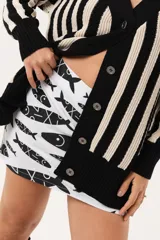 Saco oversize tejido a rayas verticales en blanco y negro, con escote en V y botones.