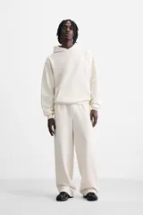 Sudadera con capucha gris confeccionada en tejido de algodón con interior rizo. Tiene manga larga, bolsillo frontal tipo canguro y acabados en rib.