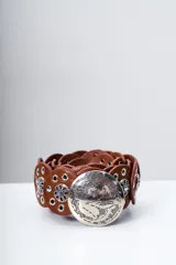 Cinto marrón de cuero con apliques metálicos plateados en forma de flor y hebilla redonda con diseño grabado.