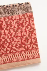 Pareo toalla rectangular de algodón con estampado étnico en tonos naranja, marrón y beige.