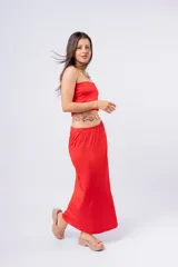Conjunto de top strapless y pollera larga con tajo lateral, ambos de color rojo. Incluye cinto dorado con apliques florales.