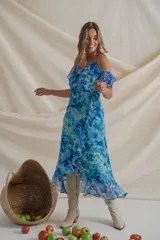 Vestido midi de gasa estampada en tonos azules, con escote cruzado, breteles finos y volados desde los breteles hasta el ruedo. Más corto adelante.