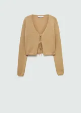 Cárdigan color beige de tejido de punto grueso, con cuello pico, diseño crop, corte recto, cierre de lazo en la parte delantera y manga larga.
