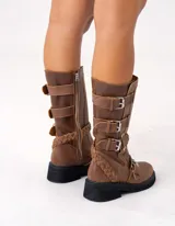 Bota de cuero color marrón con caña media, suela de goma negra, cierre lateral y hebillas ajustables. Presenta detalle trenzado en el talón.