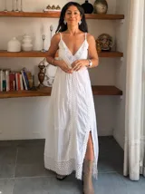 Vestido largo blanco de breteles finos, con escote en V profundo y detalles de encaje y bordados verticales en el frente y en el ruedo. Presenta una abertura lateral en la falda.