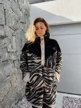 Buzo de polar con cuello alto, cierre de botones a presión y estampado de cebra en tonos beige y negro.
