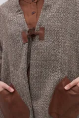 Chal de lana fina sin teñir, con calce en hombros, abrochadura con alamar de fieltro, bolsillos de cuero y terminación con flecos. Diseño exclusivo de Don Baez, hecho en Uruguay.