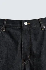 Pantalón de jean negro de corte amplio, con bolsillos delanteros y traseros, presilla portaherramientas en la pierna derecha y costuras a contratono.