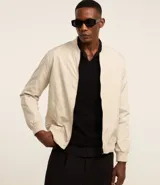 Campera bomber de sastrería color beige, con cuello alto, cierre de cremallera, bolsillos laterales, mangas largas con puños ajustados y bajo con ajustes.