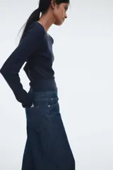 Buzo de manga larga color azul marino, de tejido de punto acanalado y corte ajustado. Presenta cuello redondo y puños con ribete blanco contrastante.