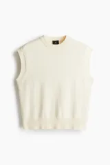 Chaleco de punto color crema con cuello redondo y ribete acanalado en cuello, sisas y bajo.