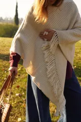 Poncho tejido en lana merino color marrón topo, con cuello redondo y terminación con flecos.