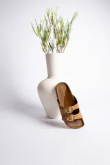 Sandalias de cuero color beige con dos tiras anchas y hebillas doradas ajustables.