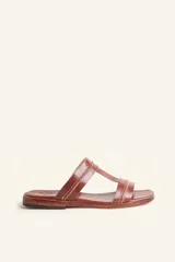 Sandalias bajas de cuero color marrón con costuras blancas a la vista.