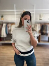 Sweater gris con cuello alto y mangas cortas tipo murciélago, con detalles de bandas horizontales negras en mangas y ruedo.