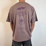 Remera lila con estampado en la espalda que incluye texto, un logo y un diseño geométrico.