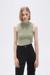 Chaleco verde pálido de punto con cuello alto y diseño trenzado.