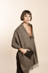 Chal de lana fina sin teñir, con calce en hombros, abrochadura con alamar de fieltro, bolsillos de cuero y terminación con flecos. Diseño exclusivo de Don Baez, hecho en Uruguay.
