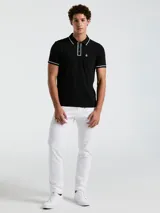 Chomba negra de piqué con cuello clásico, tapeta de dos botones y bolsillo de parche en el pecho con logo bordado. Detalles de ribete blanco en cuello y mangas.