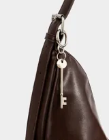 Cartera tipo saca color marrón oscuro de cuerina, con asa corta para el hombro, cierre superior y bolsillos frontales con cierre.