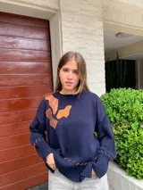 Sweater azul marino de tejido de hilo con apliques de cuero marrón y detalles de costuras en puños y ruedo.