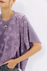Remera lila con estampado de cachemir, de mangas cortas y cuello redondo. Tiene calce amplio y corte cruzado al frente.