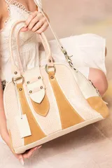 Bolso de mano estructurado con asas dobles y correa larga desmontable. Presenta un diseño combinado con paneles de cuero vacuno estampado color arena, paneles de cuero estampado color camel y paneles de gamuza color camel. Cuenta con herrajes color bronce antiguo, bolsillo trasero con cierre y bolsillo interior con cierre.