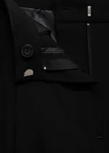 Pantalón negro de corte wide leg, tiro medio, con trabillas, bolsillos laterales y traseros. Cierre frontal oculto con botón, gancho y cremallera.