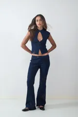 Pantalón de jean azul oscuro, corte flare, tiro medio y apliques de lentejuelas negras formando motivos florales.